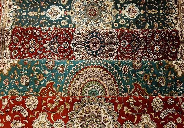 Pormenor de quatro tapetes de seda dobrados, em verde, vermelho e turquesa
